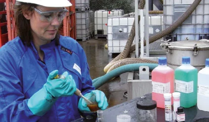 REYMKollegin in persönlicher Schutzausrüstung (PSA) entnimmt eine Flüssigkeitsprobe