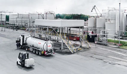 Weißer REYM_Saugwagen an einer Tankstation mit Industriekulisse im Hintergrund