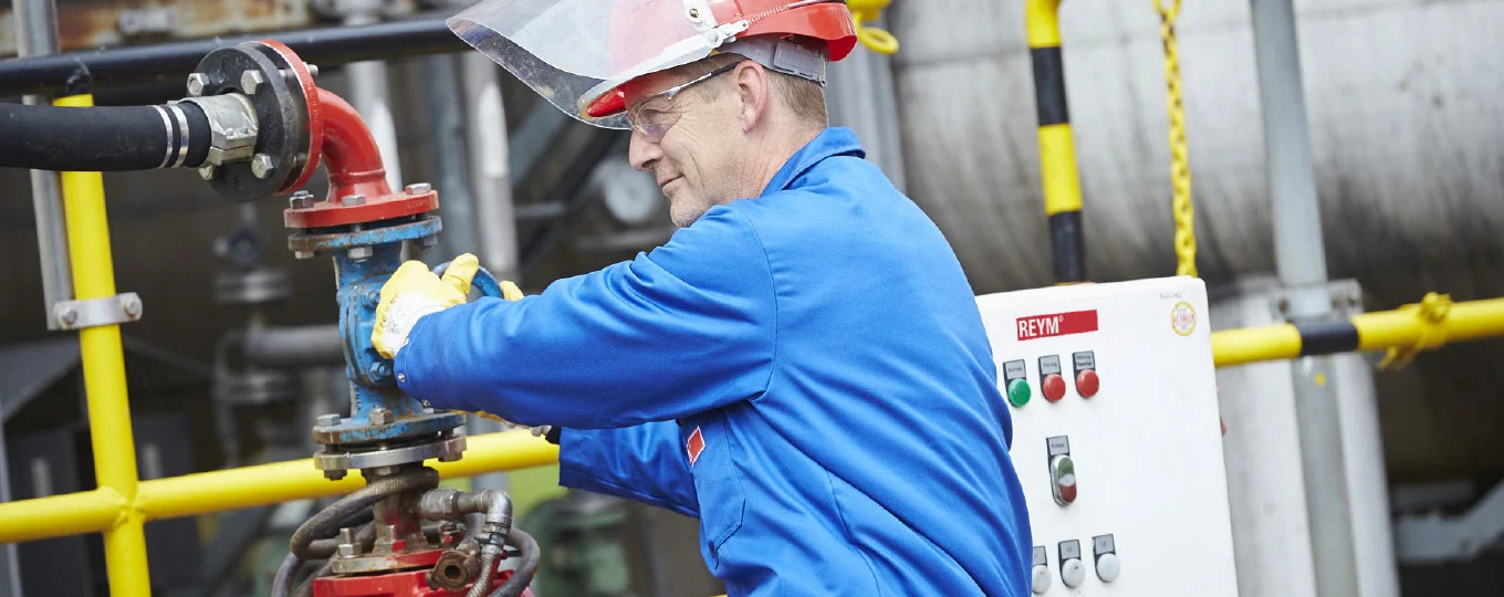 REYM-Kollege in PSA hockt an einer Rohrleitung und verschließt die Zufuhr