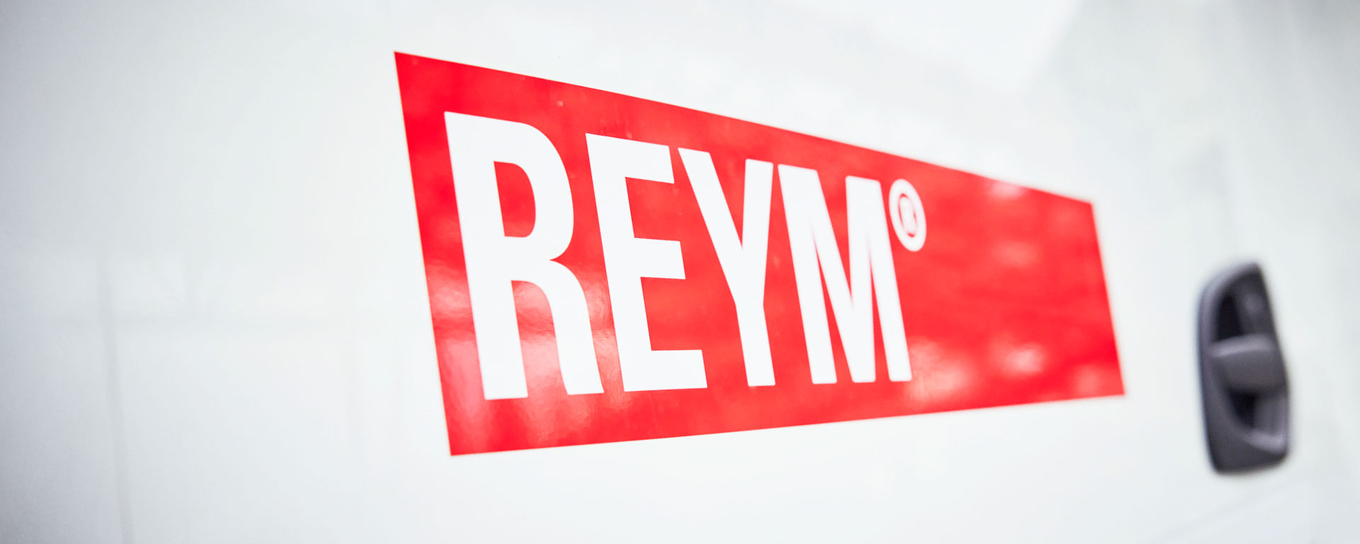 Großes rotes REYM-Logo auf einer weißen Fahrzeugtür